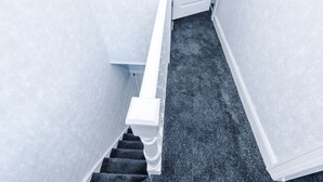 A staircase with white balusters and a dark carpeted floor.