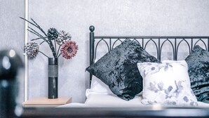 A bed with a metal headboard, a vase with flowers, and a nightstand with a book.