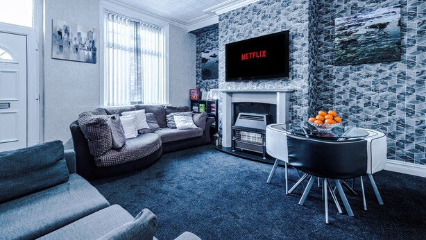 A living room with a sofa, a fireplace, a TV, and a table with oranges.