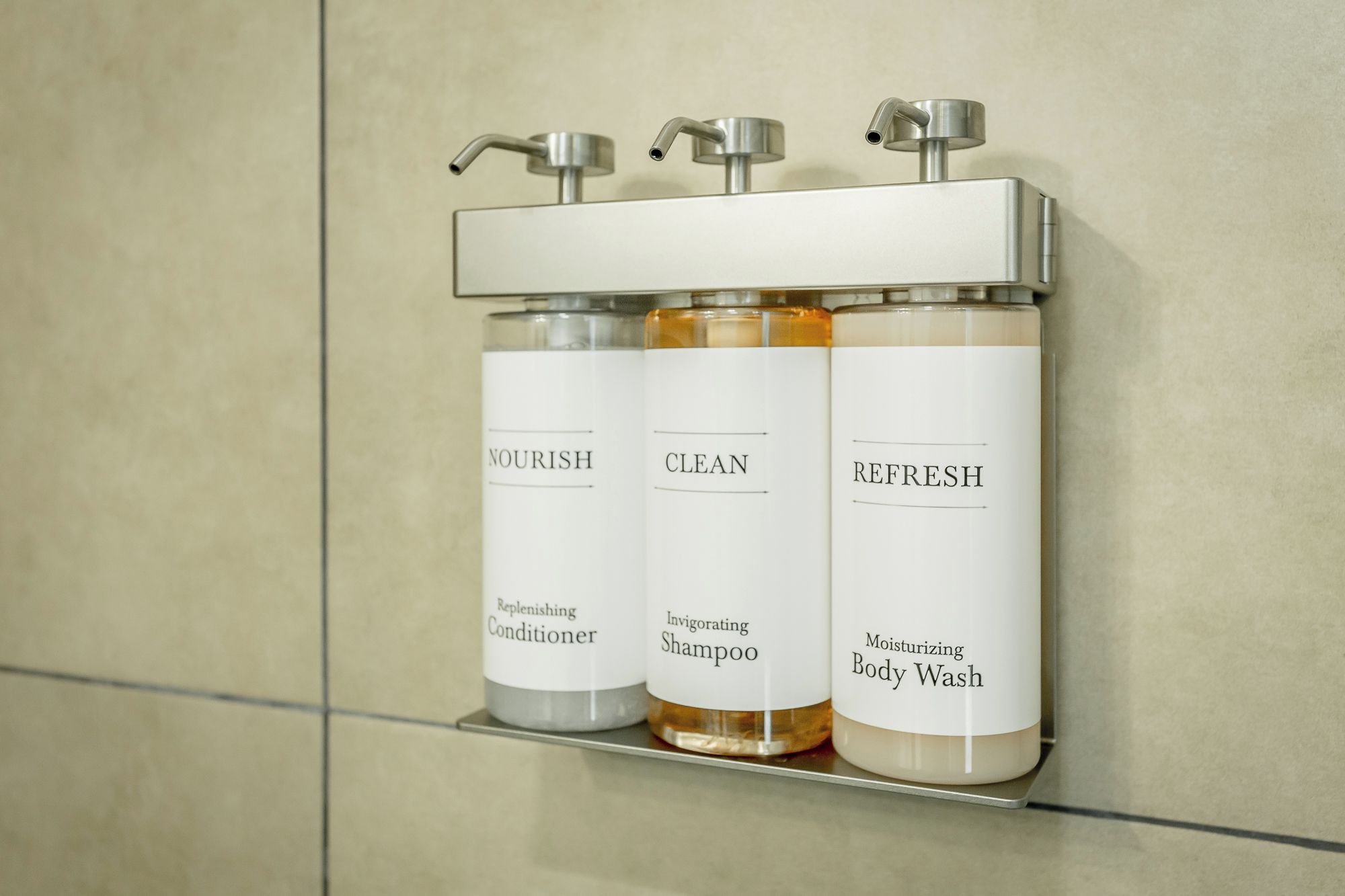 Three toiletry bottles on a shelf with taps above.
