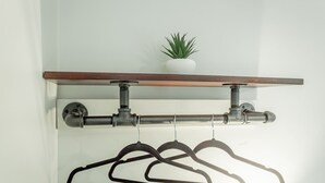 Eine Wandhalterung mit einem Blumentopf, einer Rohrleitung und Kleiderbügeln.