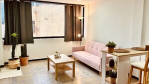 A living room with a sofa, a coffee table, a small table with a plant, and a window with curtains. - Cozy MEX-style apartment just steps from Reforma. (Ciudad de México)