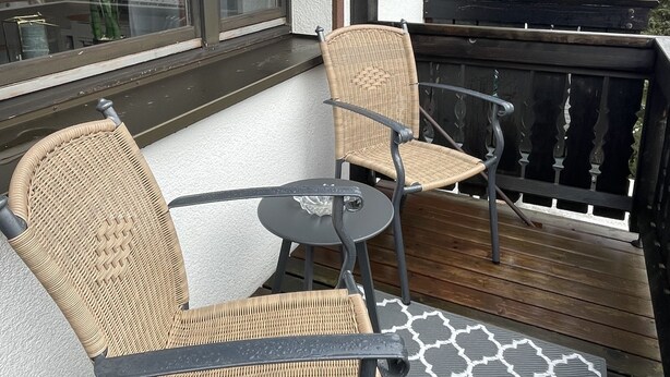 Een balkon met rieten stoelen en een tafel, met uitzicht op een schilderachtig landschap.