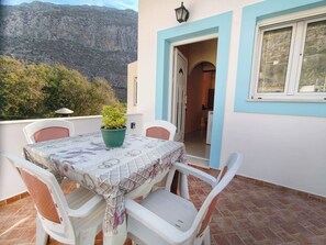 Eine Terrasse mit Tisch und Stühlen, einem Blumentopf und Blick auf einen Berg.