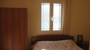 Ein Schlafzimmer mit einem Bett, einem Schrank, einem Fenster und einem Nachttisch.