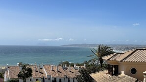 Une vue sur la côte, avec des bâtiments aux toits de tuiles rouges et un ciel bleu dégagé.