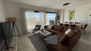 Un salon moderne avec un canapé marron, une table basse et un coin repas comprenant une table et des chaises.
