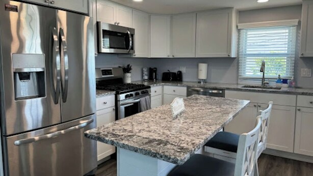 A modern kitchen with stainless steel appliances, granite countertops, and white cabinetry.