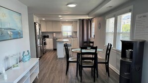A modern kitchen with white cabinets, a central island, and a dining area with a round table and chairs.