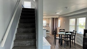 A staircase leading to a dining area with a kitchen in the background.