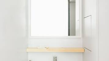 A modern bathroom with a white sink, a mirror, and a wooden vanity.