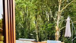 A wooden deck with a hot tub, a wicker sofa with cushions, and a compost bin.