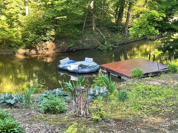 Un río tranquilo con un muelle de madera y un bote inflable.