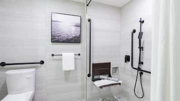 Ein modernes Badezimmer mit Toilette, einer Dusche inklusive Handbrause, einem Handtuchhalter und einem gerahmten Bild an der Wand.