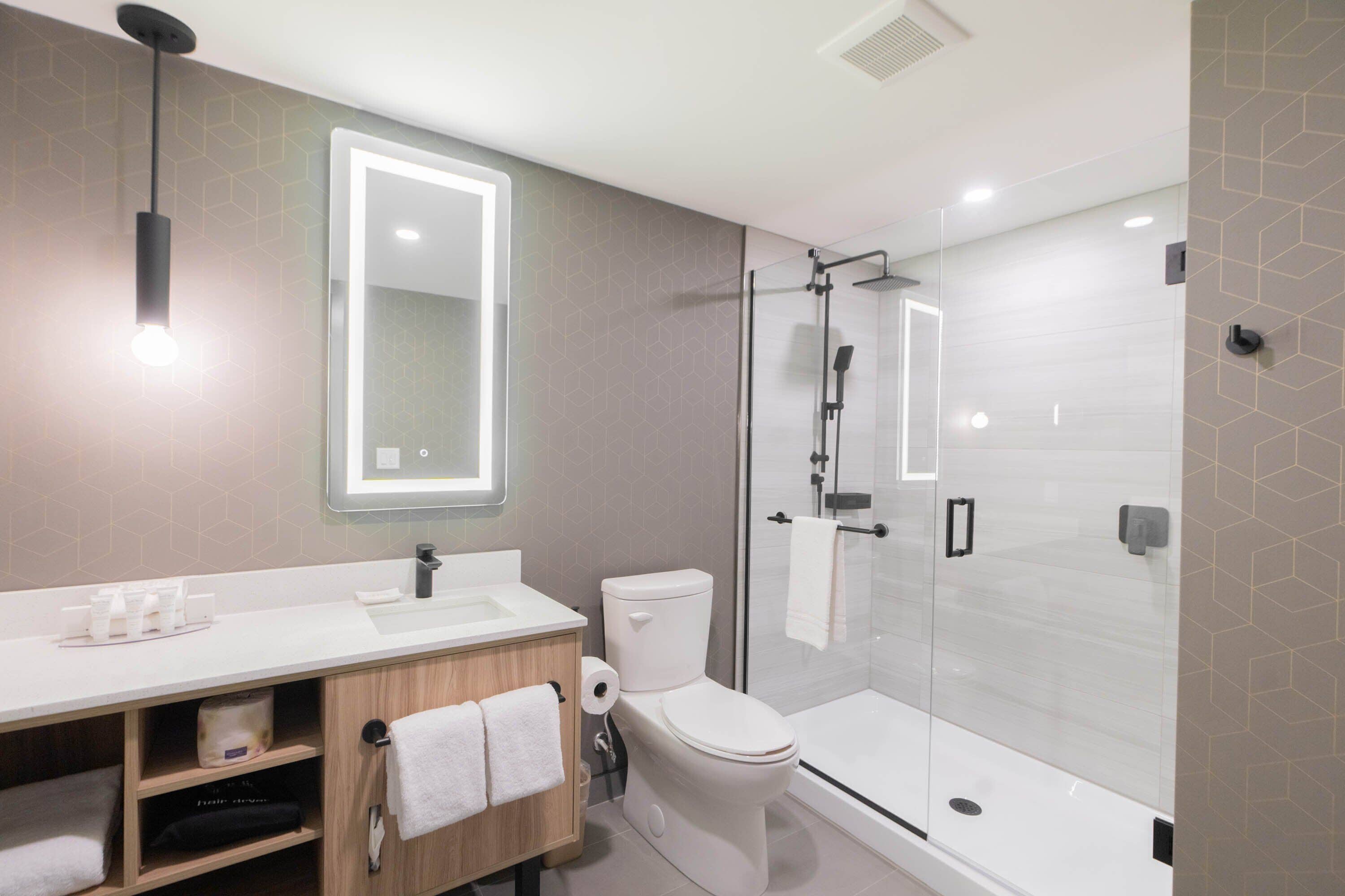 A modern bathroom with a white sink, toilet, and shower.