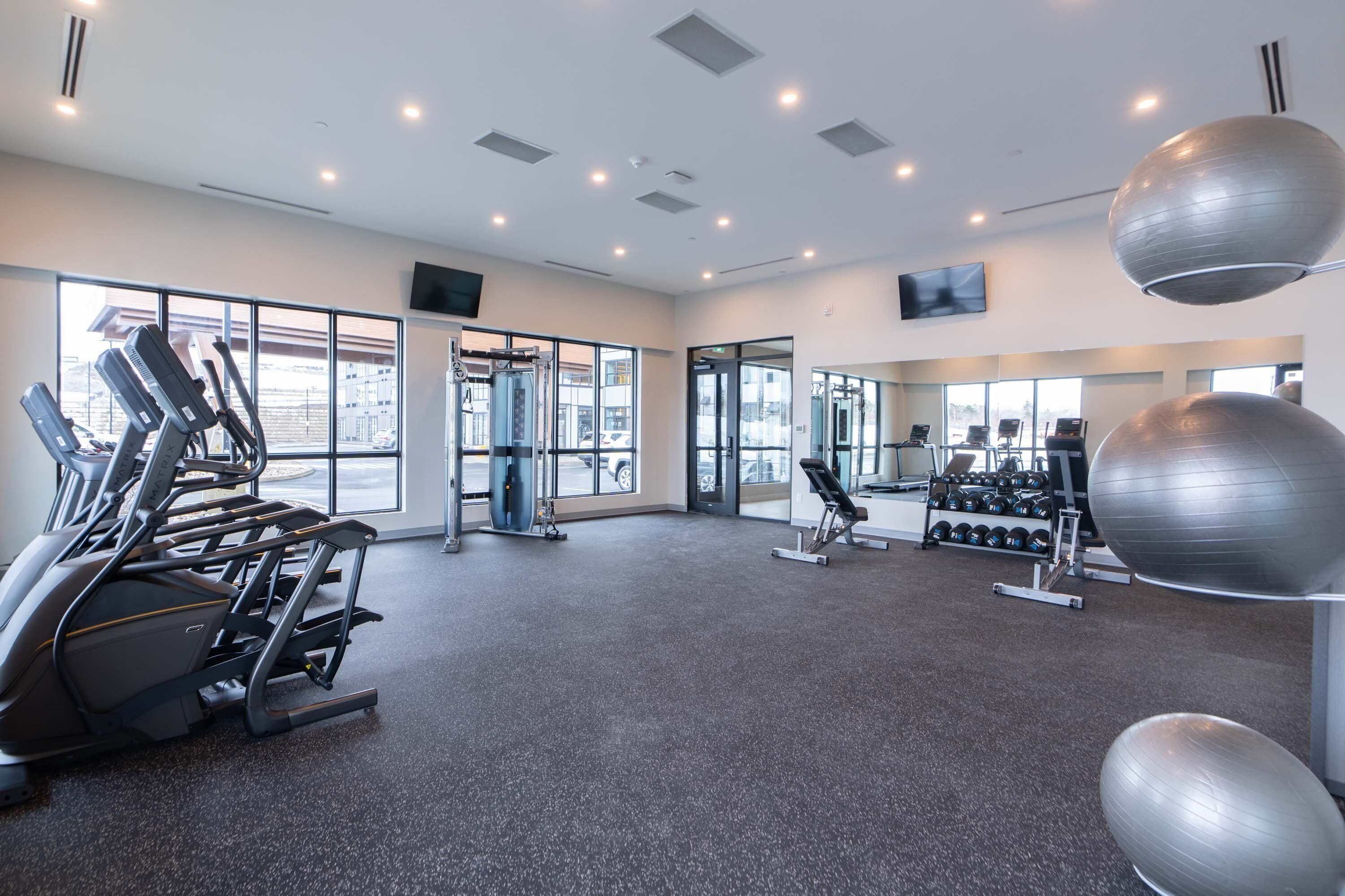 A modern gym with cardio machines, weightlifting equipment, and exercise balls.
