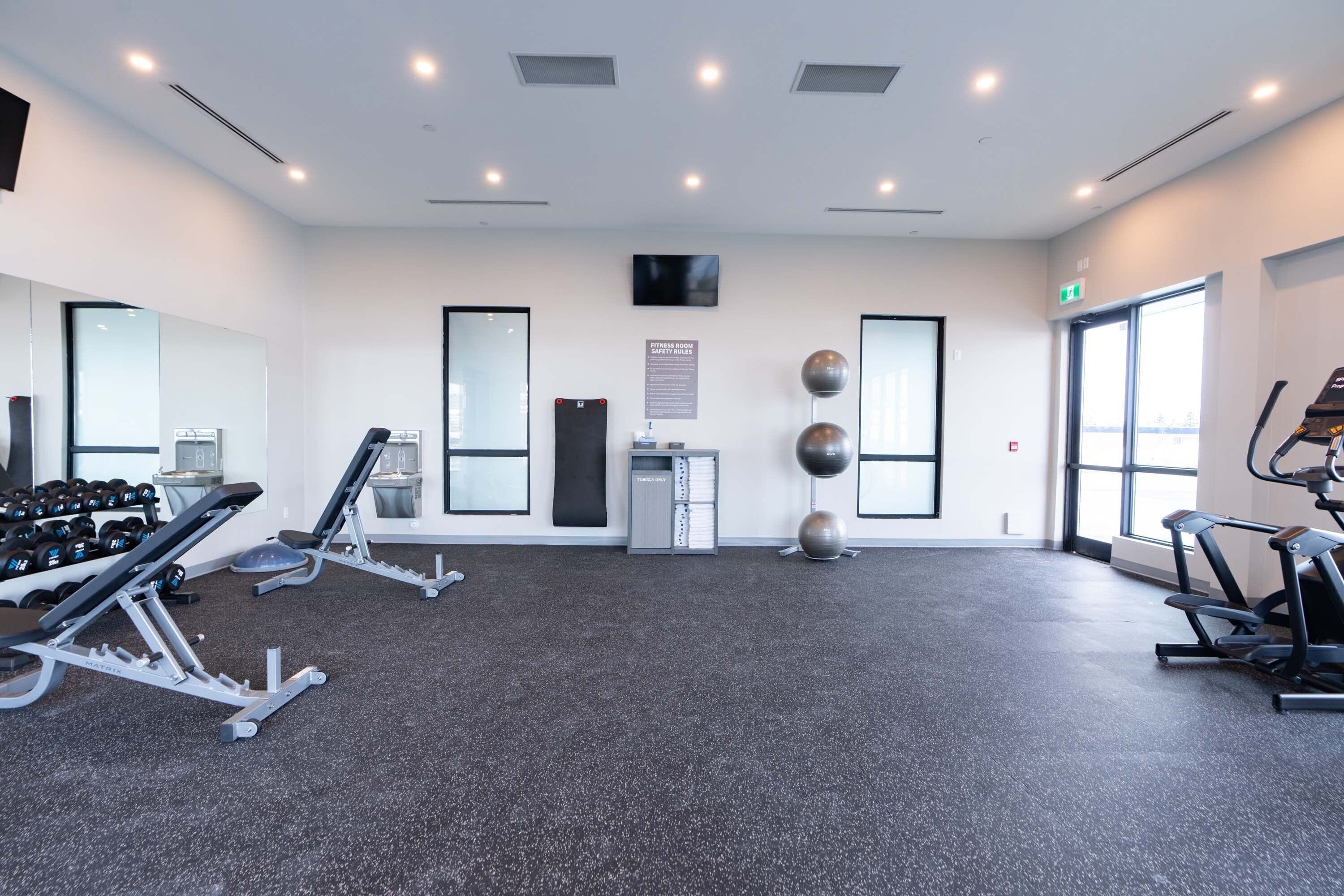 Un gimnasio moderno con equipo cardiovascular, máquinas de pesas y un espejo.