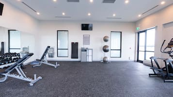 Un gimnasio moderno con equipo cardiovascular, máquinas de pesas y un espejo.