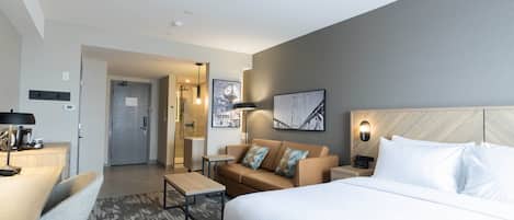 Una habitación de hotel con una cama, un sofá, un escritorio y una silla.