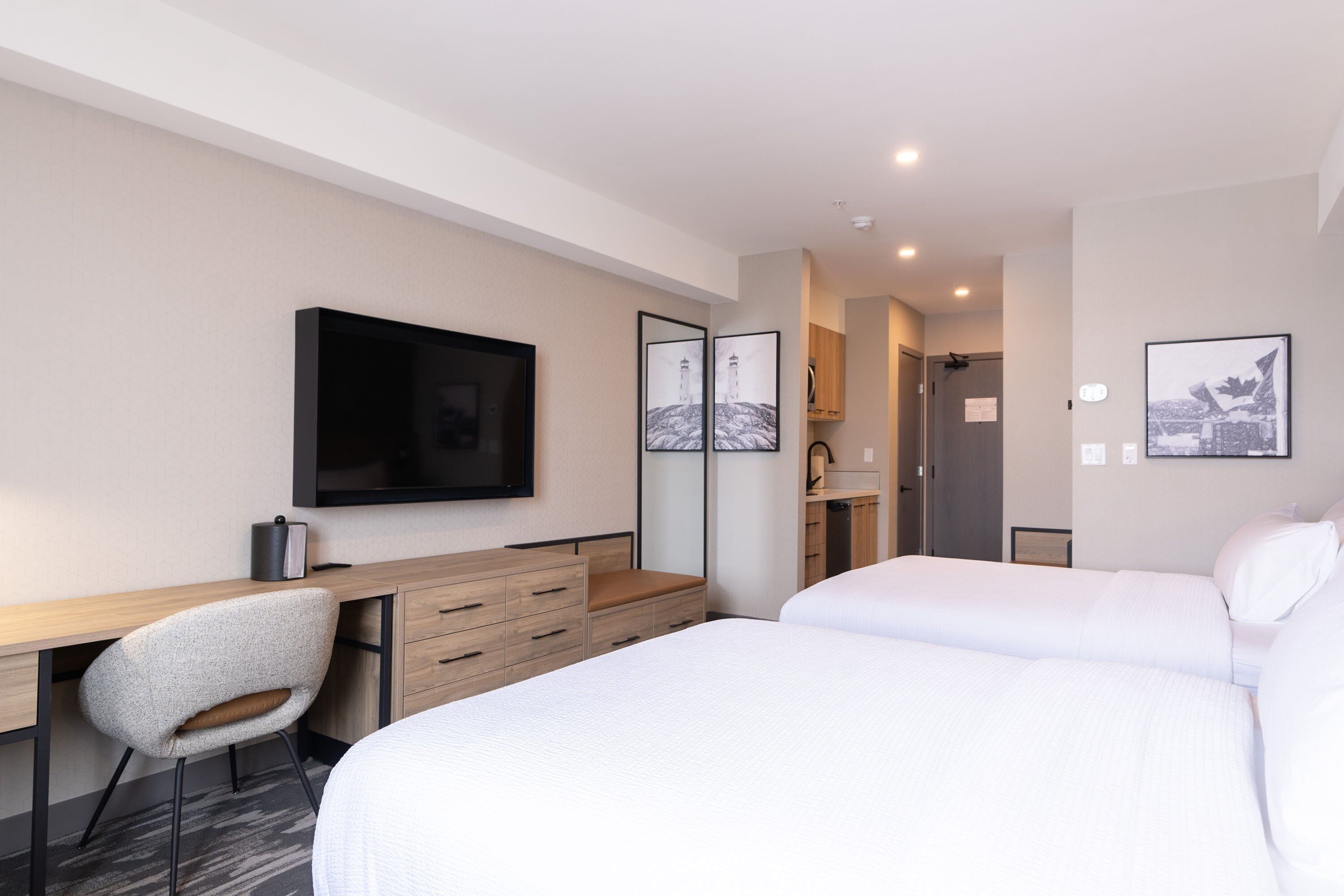 Een moderne hotelkamer met een bed, een bureau, een stoel en een televisie.