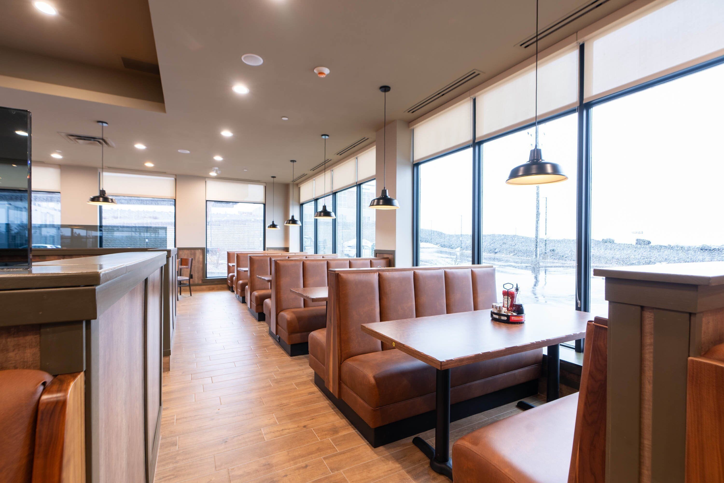 A restaurant with wooden flooring, leather booths, and pendant lighting.