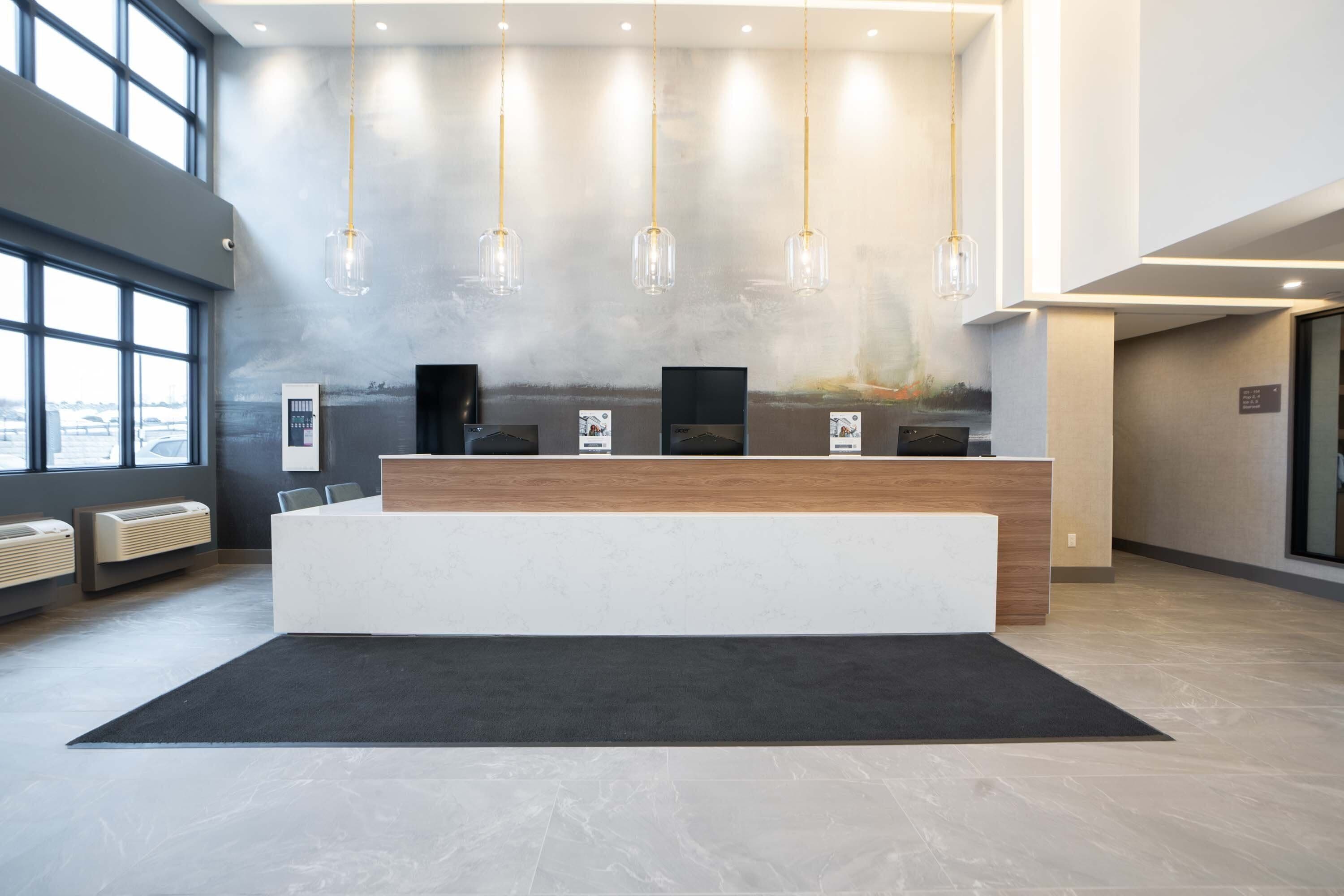 Zona de recepción con diseño moderno, que incluye un mostrador de recepción, lámparas colgantes y un amplio ventanal con vistas al exterior.