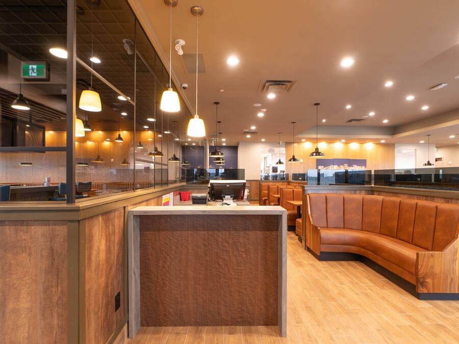 Un restaurant moderne avec des meubles en bois, des luminaires suspendus et un comptoir central.