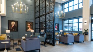 Un vestíbulo moderno con sofás grises, un separador decorativo negro y candelabros.