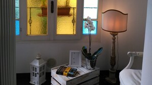 A room with a large arched window, a white lamp, a wooden crate with books, and a white chair. - Casa di Ellen 200 meters from the beach (string:GE)