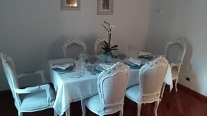 Et spisebord med hvide stole, en vase med blomster og glas.
