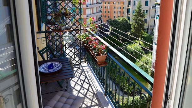 A balcony with a view of a cityscape, a table with chairs, and potted plants. - Casa di Ellen 200 meters from the beach (string:GE)