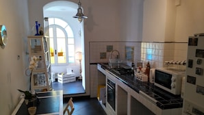 A modern kitchen with white cabinetry, a black countertop, and a dining area with a table and chairs. - Casa di Ellen 200 meters from the beach (string:GE)