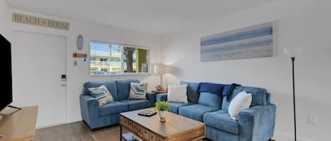A living room with a blue sofa, a wooden coffee table, and a lamp.