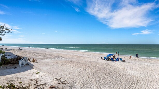 A wide sandy beach with a clear blue sky and calm sea. - Charming Beach Condo Steps to Beach | Heated Pool | Sleeps 4 (Bradenton Beach)