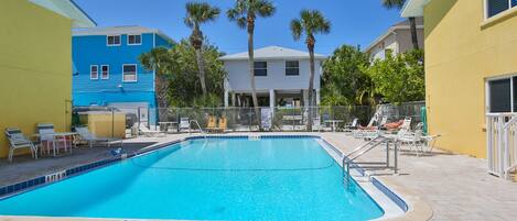 A swimming pool with a 8 FT 6 IN depth marker, surrounded by lounge chairs and palm trees.