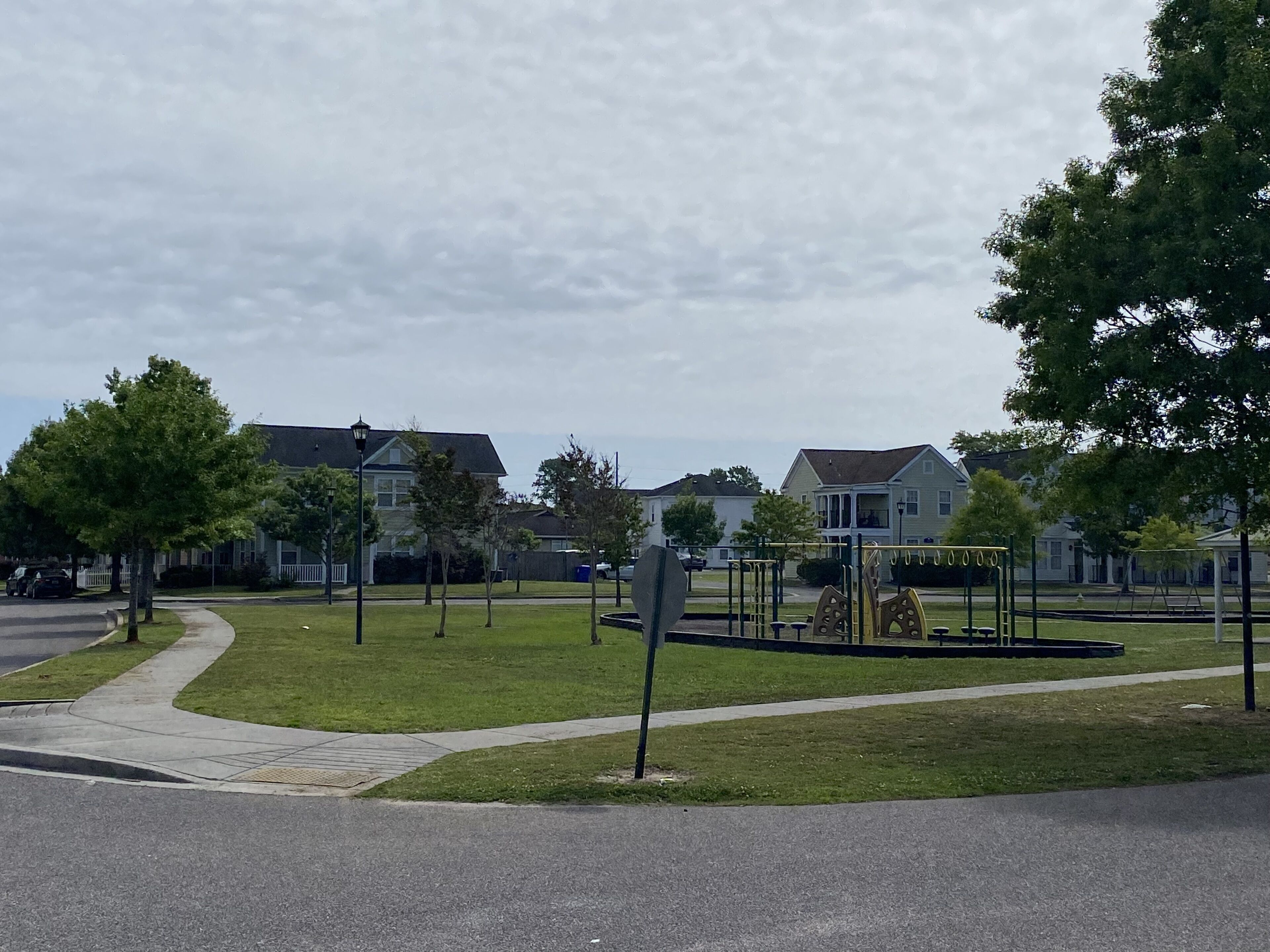 A residential area with houses, a playground, and a sidewalk.