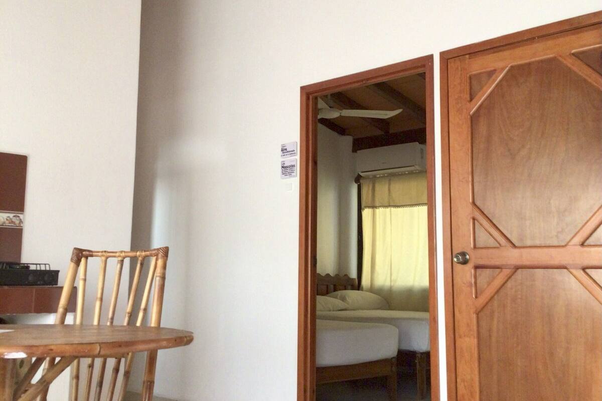 Une pièce avec une porte en bois, un lit et un coin repas comprenant une table et des chaises.