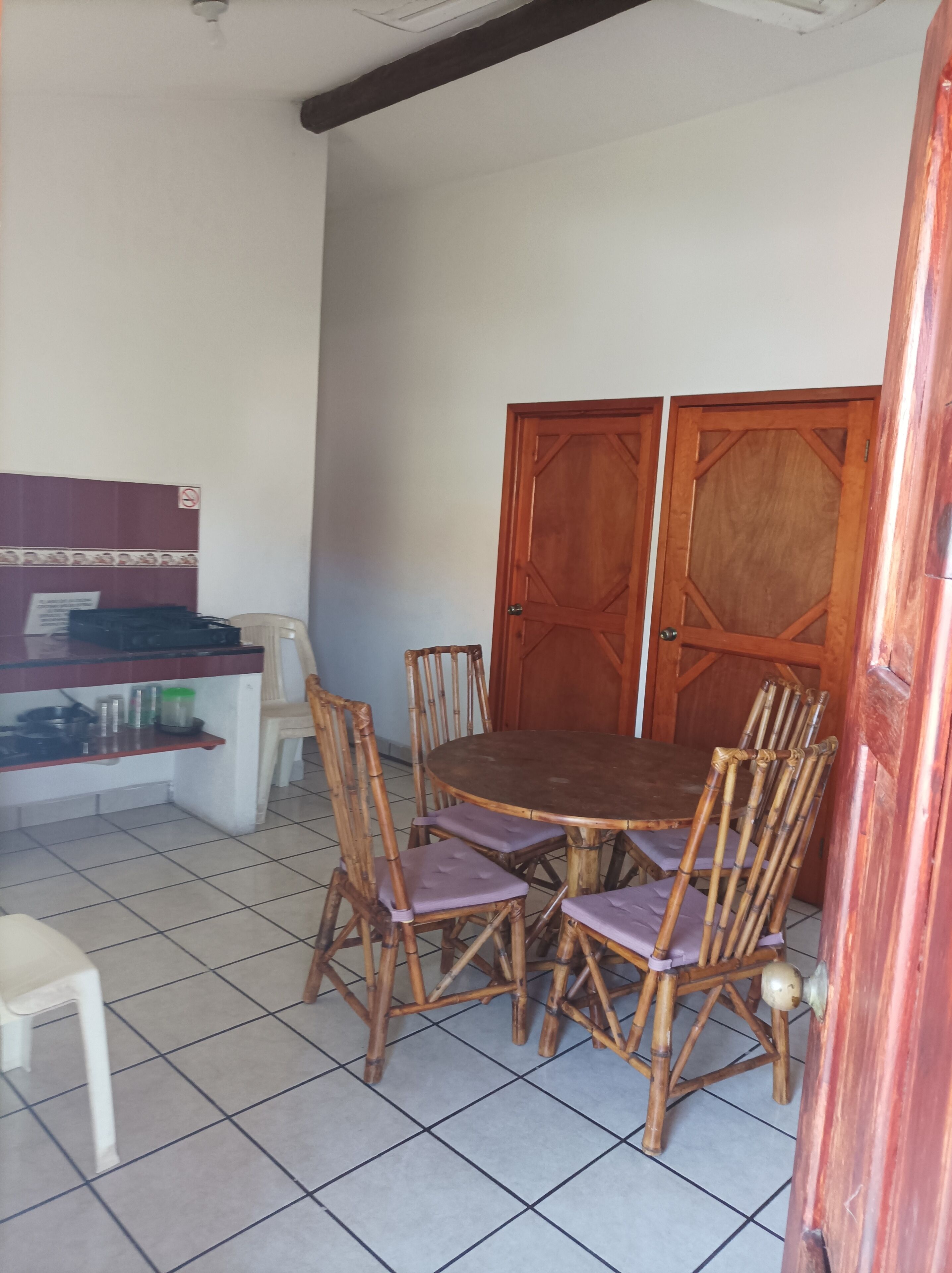 Un coin repas avec une table et des chaises en bois, un comptoir de cuisine et une porte en bois fermée.