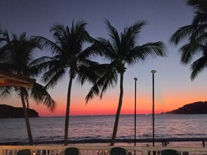 Une vue sur le coucher de soleil, avec des palmiers et une plage.