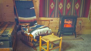 A cozy cabin interior with a rocking chair, a small wooden table, and a wood-burning stove. - Smith Lake Cabin with Game Room (Marcell)