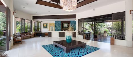 Un espacio interior amplio con una mesa de centro, arreglos de asientos y un jarrón decorativo.
