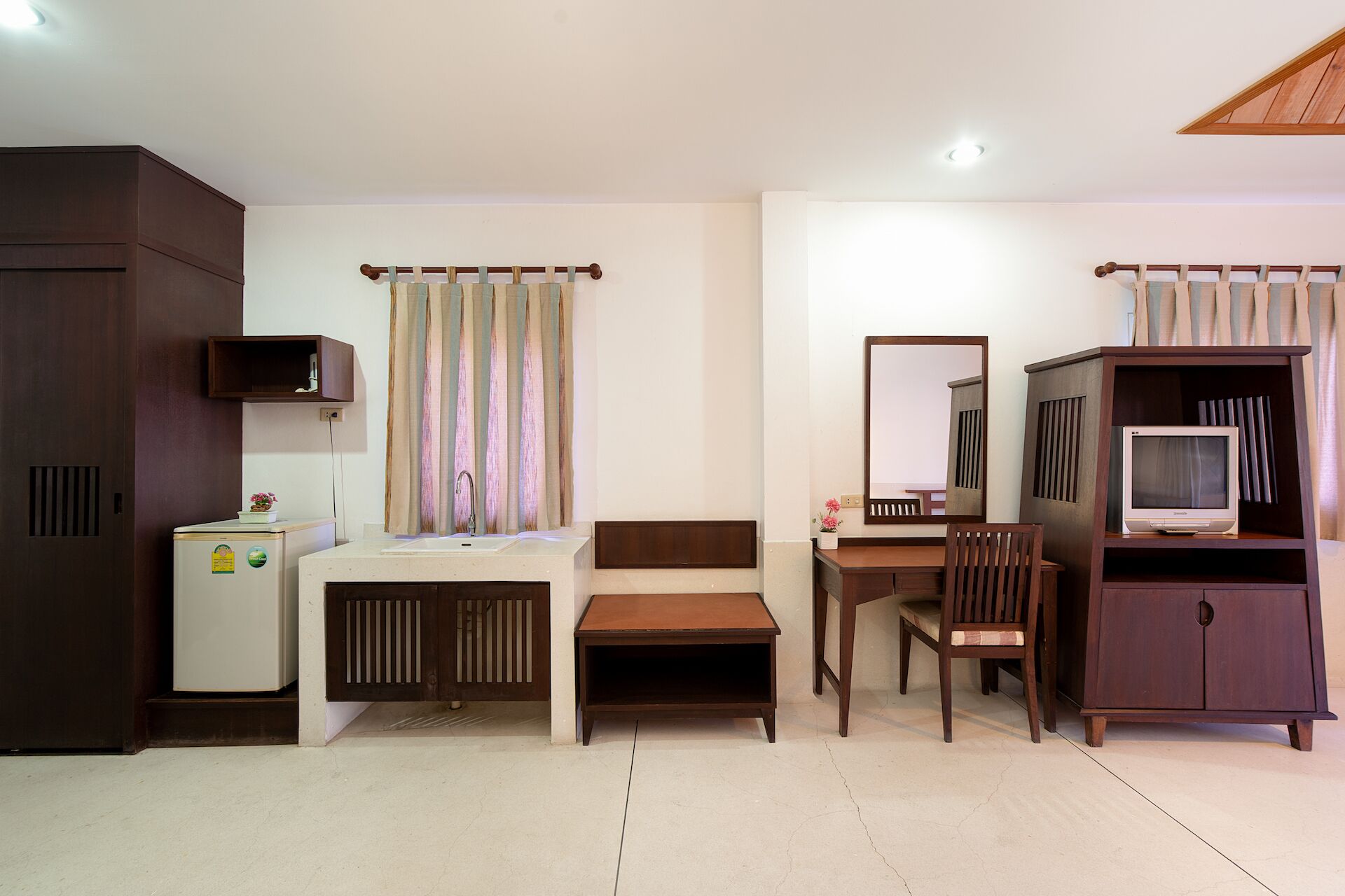 A compact hotel room with a bed, a desk, a chair, a television, and a wardrobe.