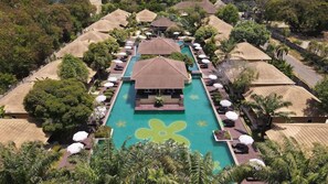 An aerial view of a resort with multiple overwater bungalows, a central pool, and lush tropical landscaping. - East Sea Paradise Hotel (Pattaya)