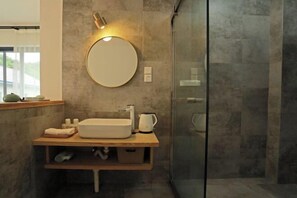 A modern bathroom with a round mirror, a white sink, and a glass shower enclosure. - Wonder Villa (Deqing)