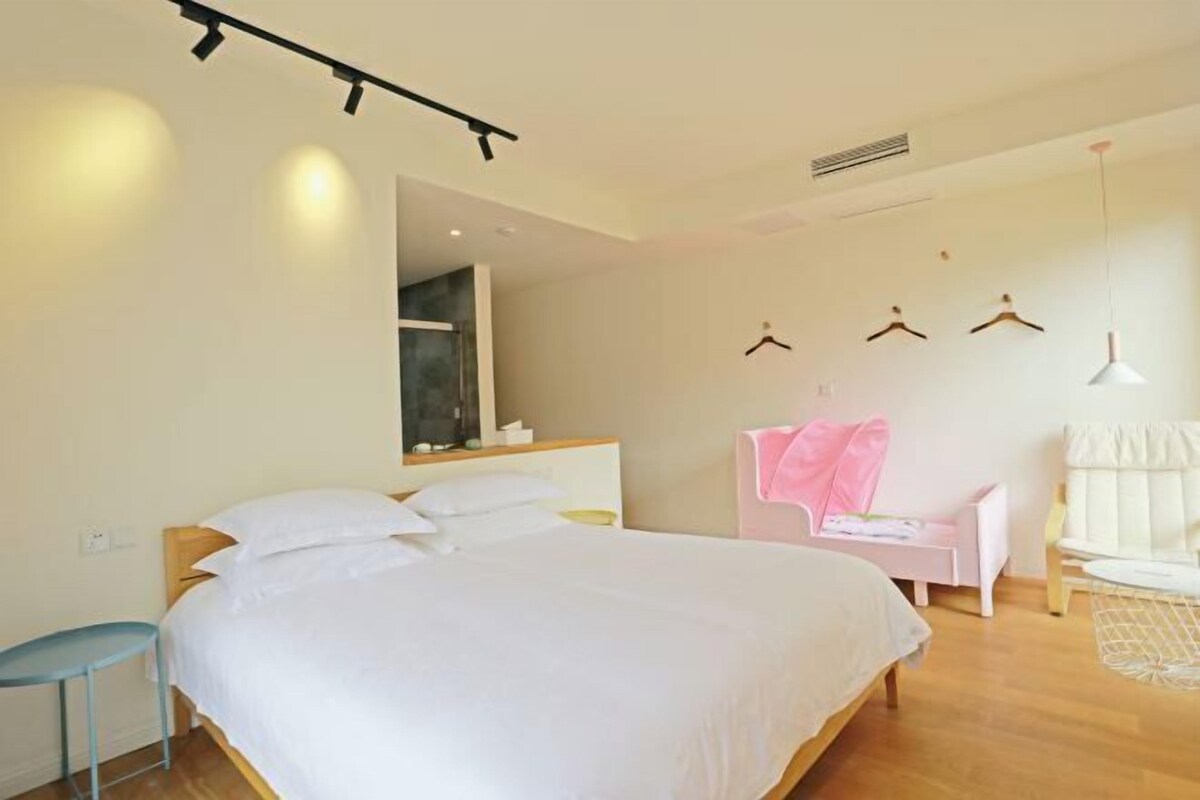 A bedroom with a bed, a chair, a table, and a wardrobe.