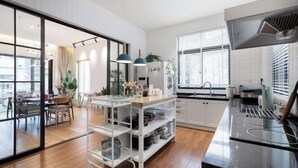 A modern kitchen with a black countertop, white cabinets, and a glass door leading to a dining area. - Wonder Villa (Deqing)