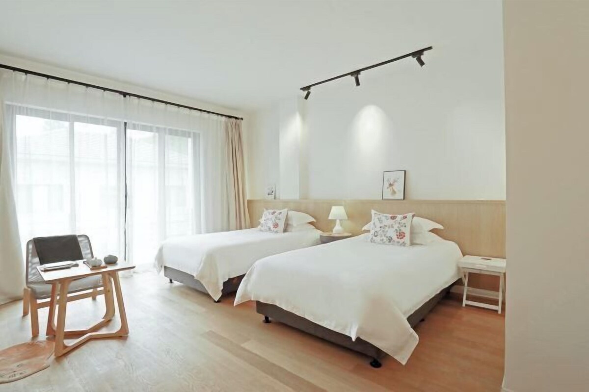A hotel room with two beds, a desk, and a chair.