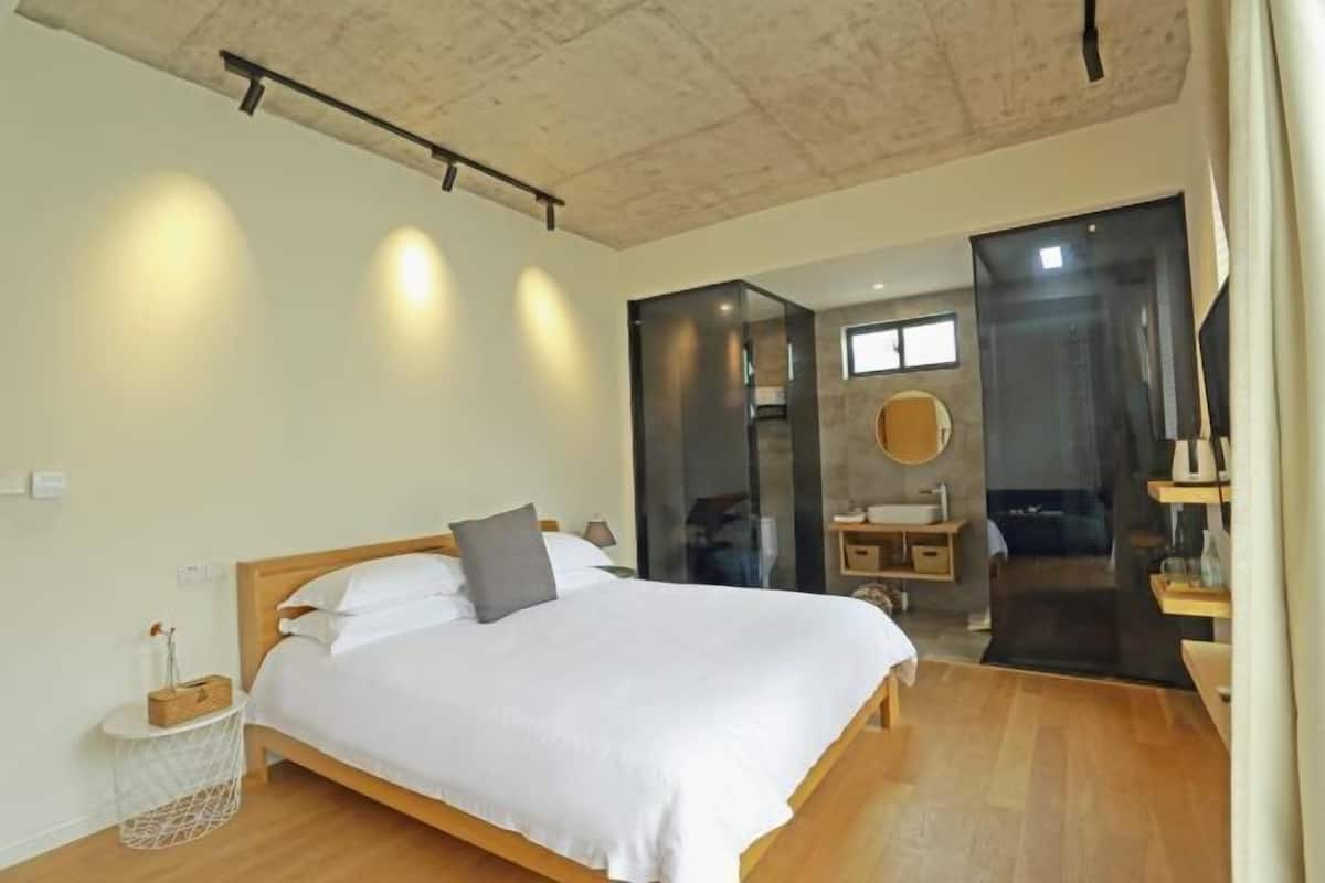 Un dormitorio con cama, mesita de noche y una ventana pequeña.