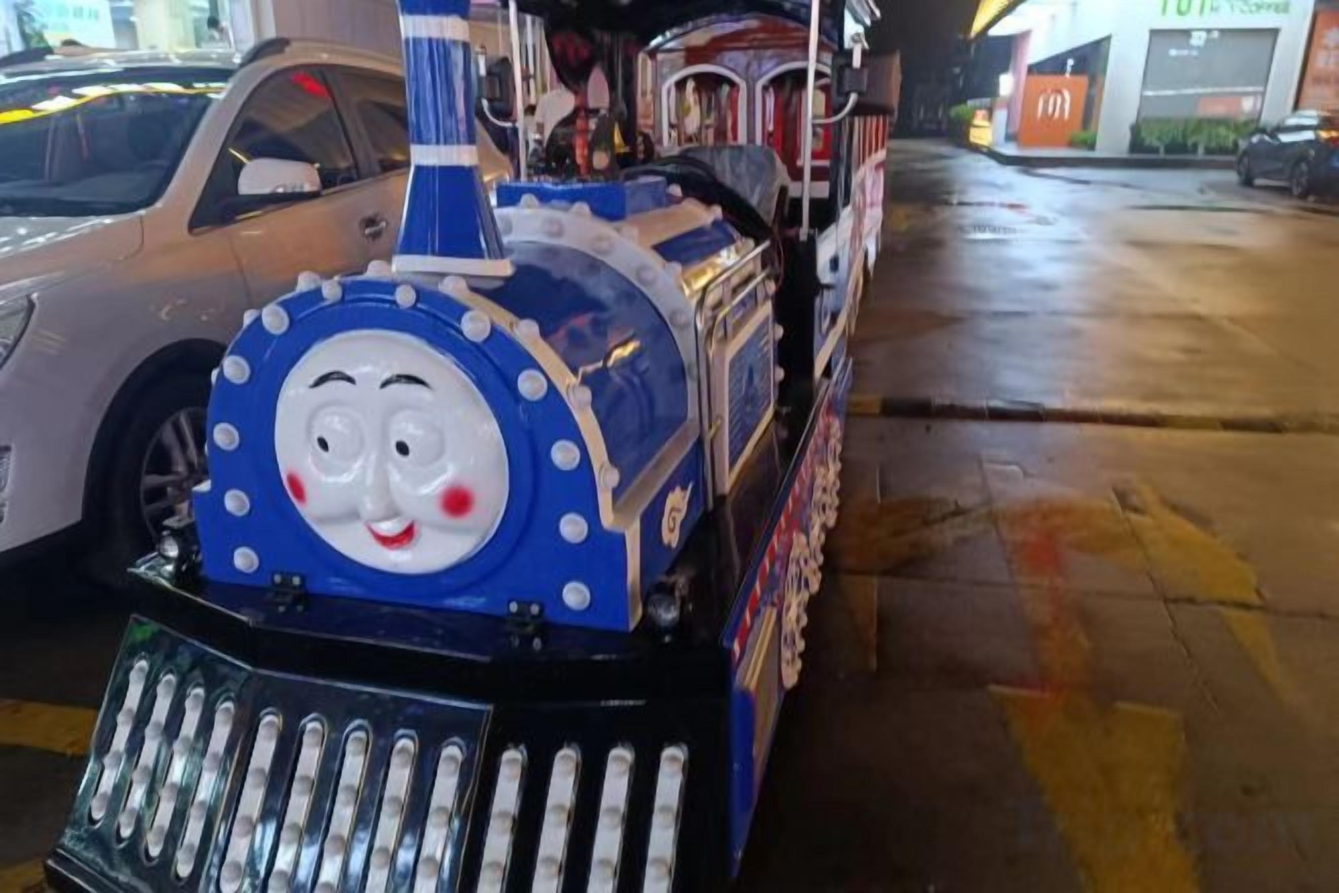 Ein Zug mit einem lächelnden Gesicht, abgestellt auf nasser Fahrbahn.