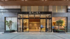 A hotel entrance with a modern design, featuring a glass facade and a wooden ceiling.
